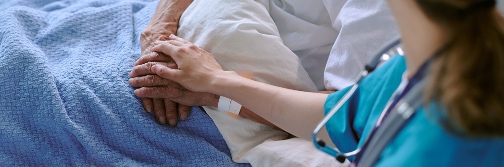 senior,patient,lying,in,hospital,bed,receiving,comforting,touch,from
